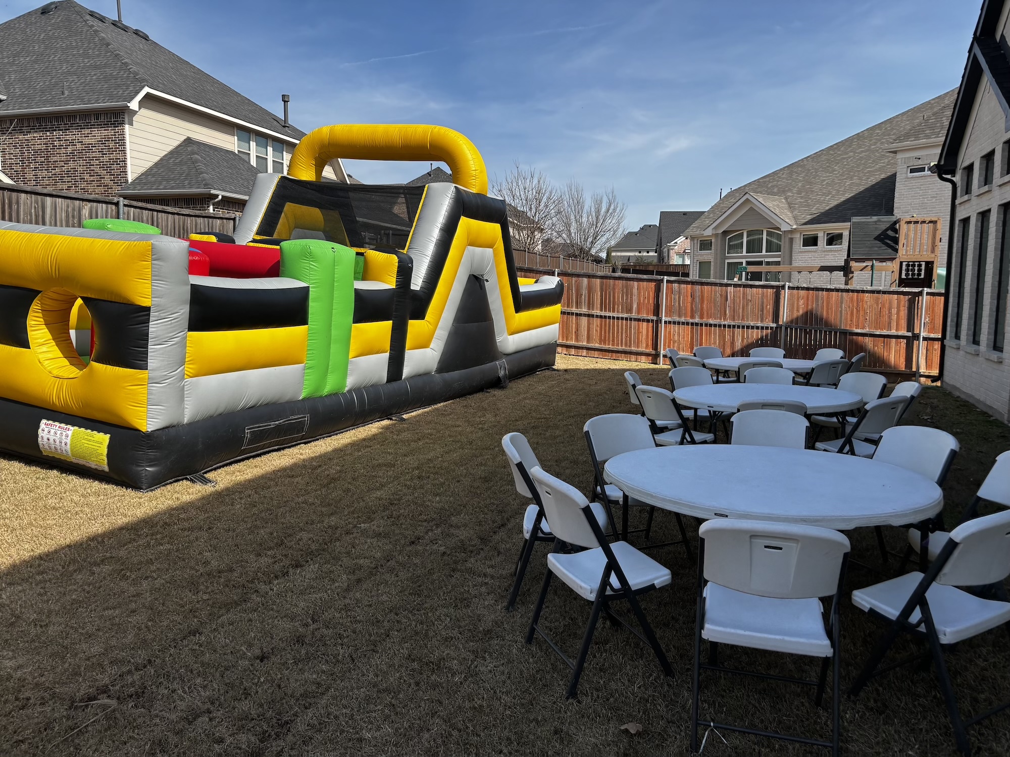Full backyard party setup with obstacle course, tables and chairs in Dallas County