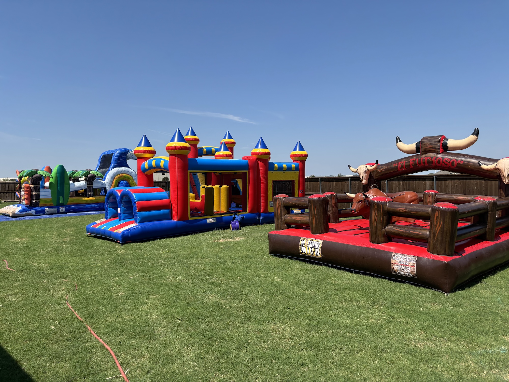 Bounce houses and mechanical bull set up for a backyard party in Dallas County